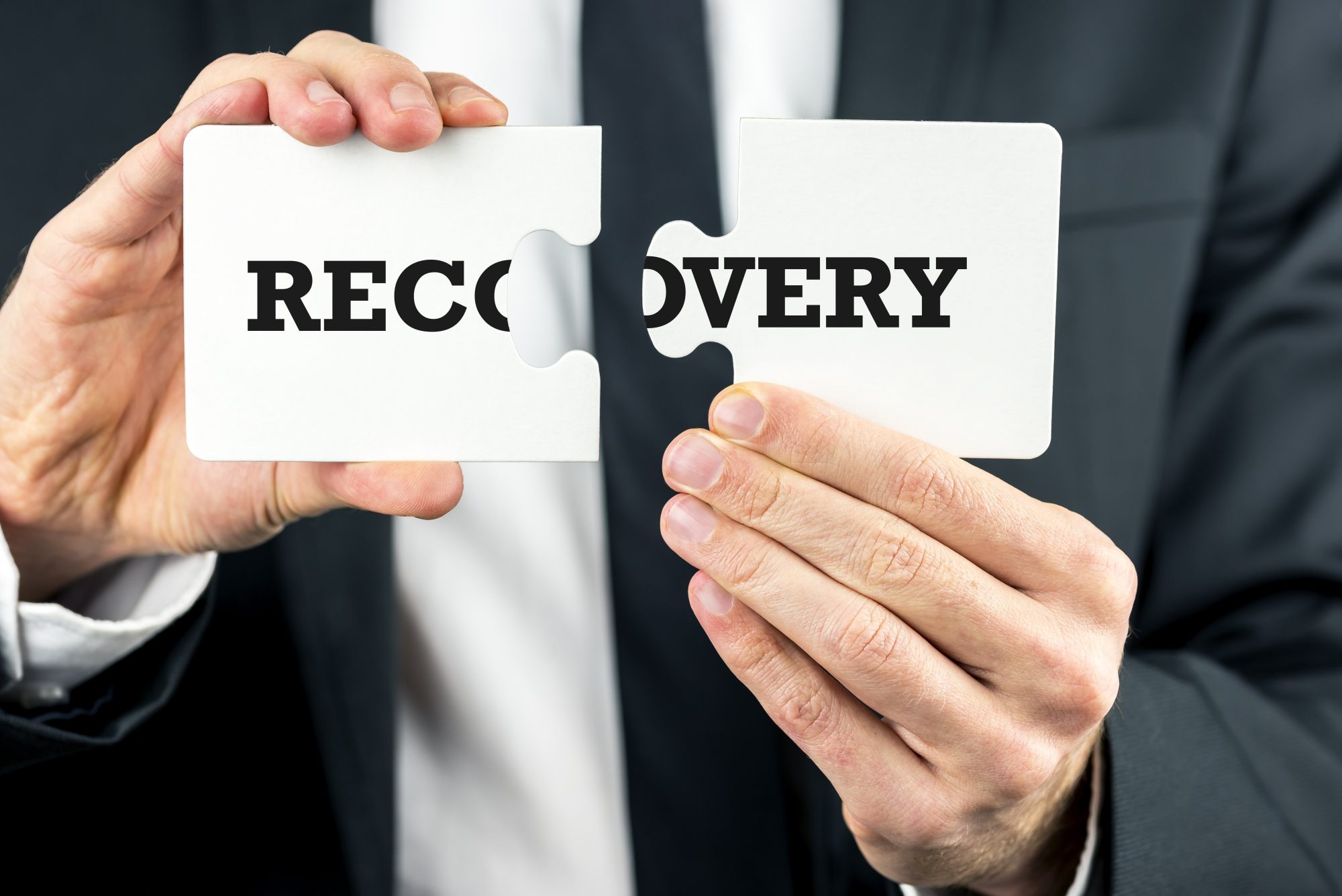 Businessman,Holding,The,Word,Recovery,Split,Over,Two,Puzzle,Pieces